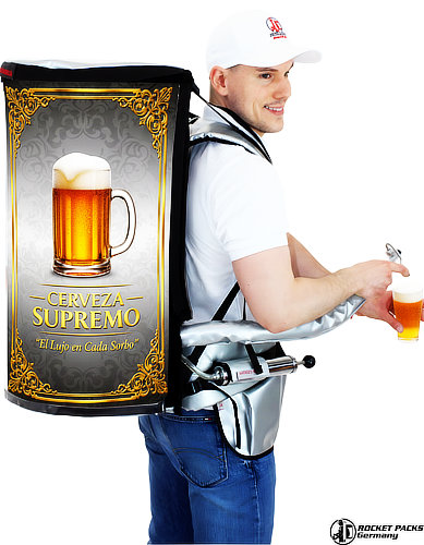 Un promotor sonriente utilizando una mochila dispensadora de bebidas Rocketpacks en un festival al aire libre, sirviendo una bebida fría directamente desde el grifo integrado, con un gran número de asistentes de fondo disfrutando del sol.